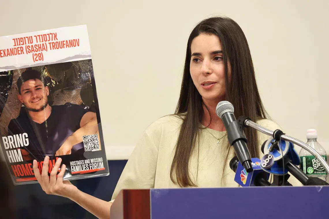 NEW YORK, NEW YORK - AUGUST 27: Sapir Cohen, a freed Israeli hostage, holds up a poster of her boyfriend Sasha Trupanov as she speaks during an Evening of Unity event at Yeshiva University’s Stern College for Women on August 27, 2024 in New York City. Cohen spoke to the school's female undergraduate student body about her experience being captured by Hamas terrorists on October 7, along with her boyfriend, Sasha Trupanov, from Kibbutz Nir Oz in Israel. She was freed from captivity in November as part of a temporary cease-fire deal brokered by Qatar and the United States between Hamas and Israel. Her boyfriend is among the roughly 100 hostages still remaining in captivity.   Michael M. Santiago/Getty Images/AFP (Photo by Michael M. Santiago / GETTY IMAGES NORTH AMERICA / Getty Images via AFP)