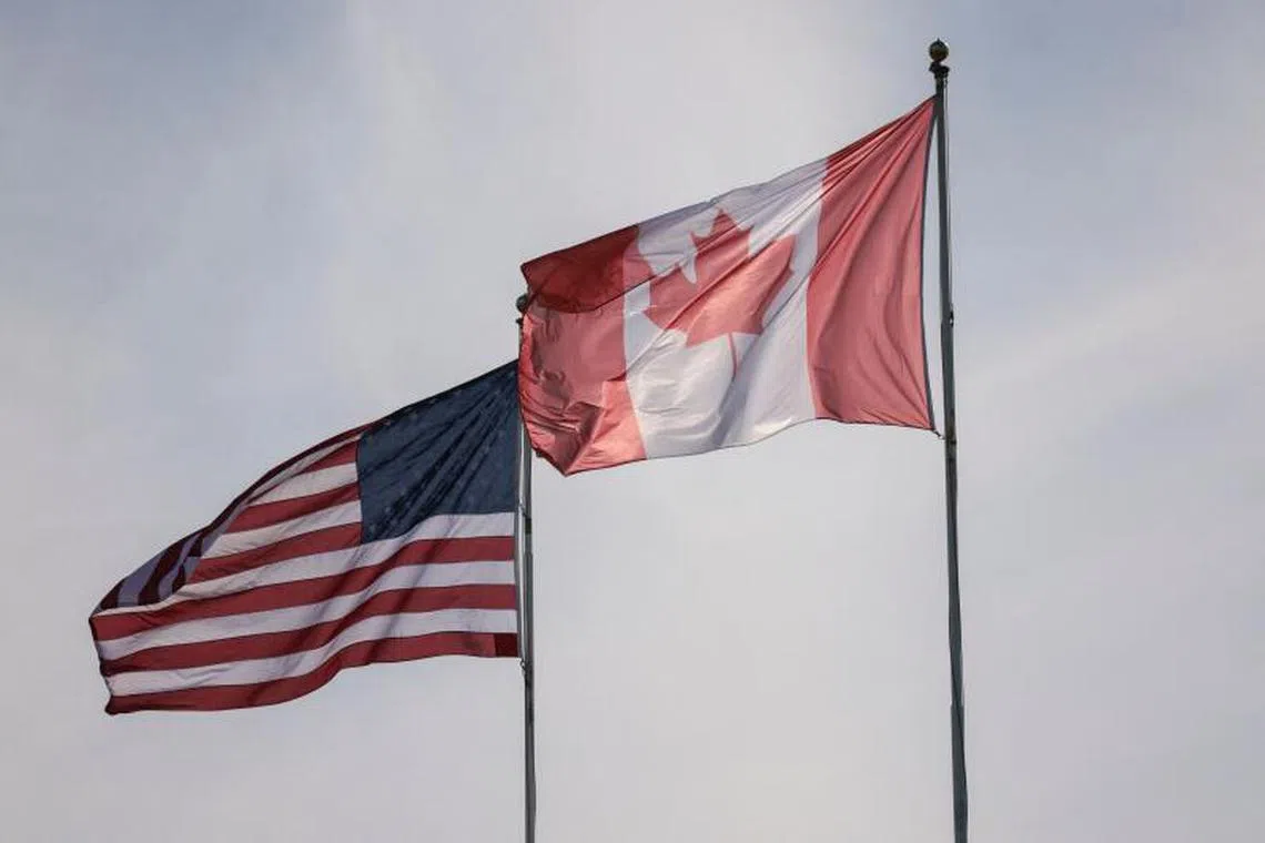The US and Canadian flags are pictured at Peace Arch Historical State Park in Blaine, Washington, on March 5, 2025. The United States will allow a one-month exemption from tariffs on auto imports from Canada and Mexico, the White House said on March 5, a day after steep levies on its neighbors came into effect. (Photo by Jason Redmond / AFP)