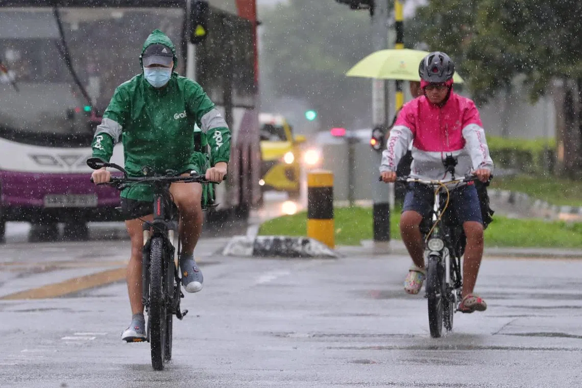 Delivery riders crossing the junction of Pasir Ris Drive 1 and Drive 8 during a downpour on Oct 21, 2022.