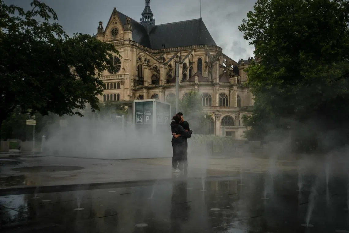 A couple embracing on a rainy day in front of the Saint-Eustache church in central Paris, on July 21, 2025. 