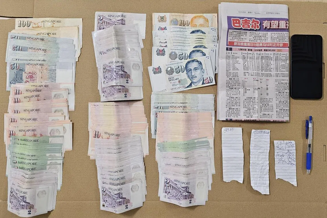 Cash, a mobile phone and gambling paraphernalia seized in a police enforcement operation on March 17, 2024. 
