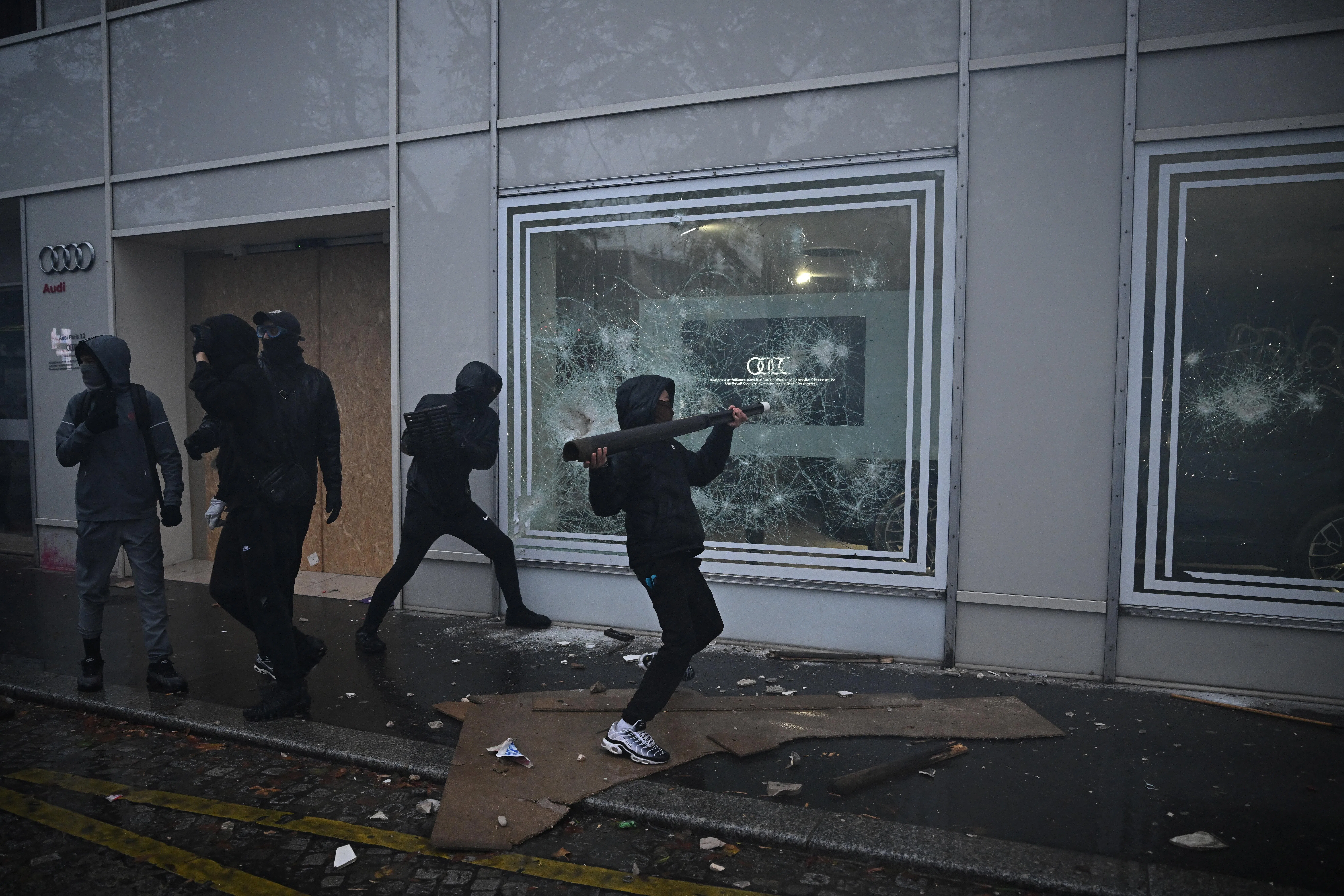 Masked protesters smash the window of a Audi store in Paris.