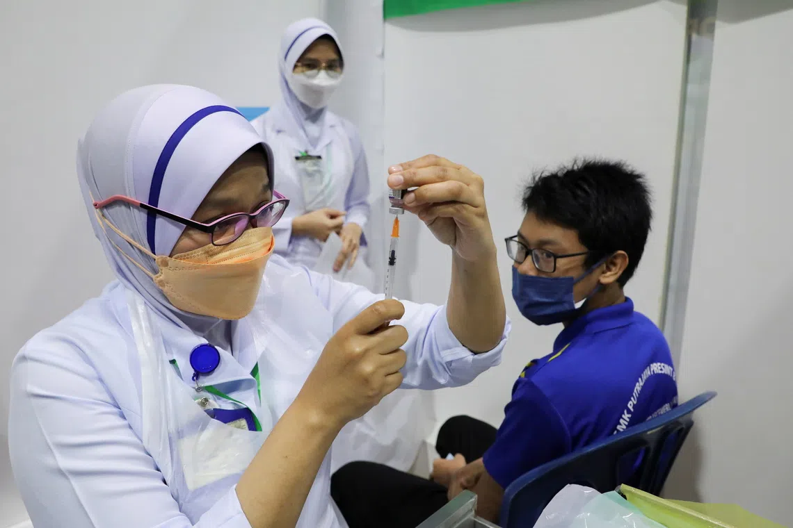 A nurse prepares a dose of the Pfizer vaccine against Covid-19 for a secondary school student at a school, in Putrajaya, Malaysia, in 2021.