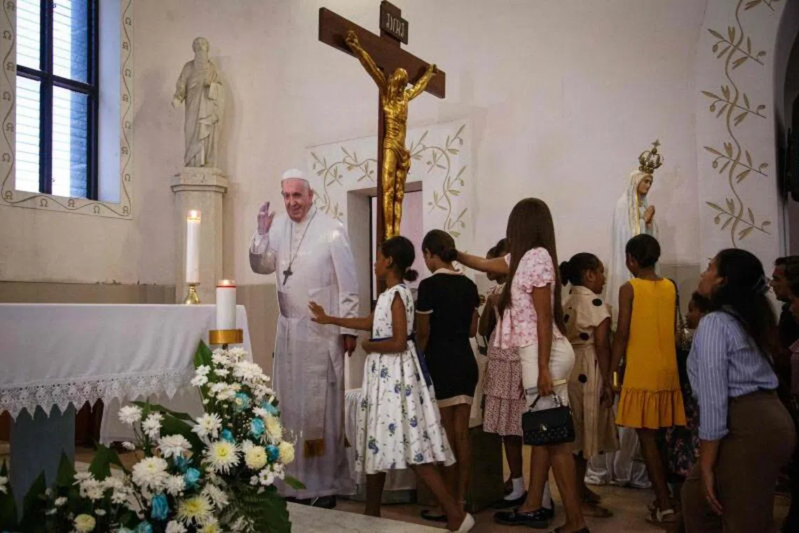 TOPSHOT - Catholics gather to touch a life-size cardboard cutout of Pope Francis, who is currently hospitalized in Rome for pneumonia, during Sunday mass at the Church of Santo Antonio de Motael in Dili, East Timor, on February 23, 2025. (Photo by VALENTINO DARIELL DE SOUSA / AFP)
