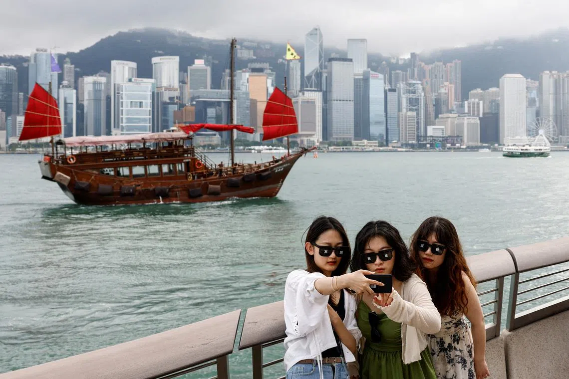 FILE PHOTO: Tourists take photos in front of Victoria Harbour, in Tsim Sha Tsui, in Hong Kong, China April 29, 2024. REUTERS/Tyrone Siu/File Photo
