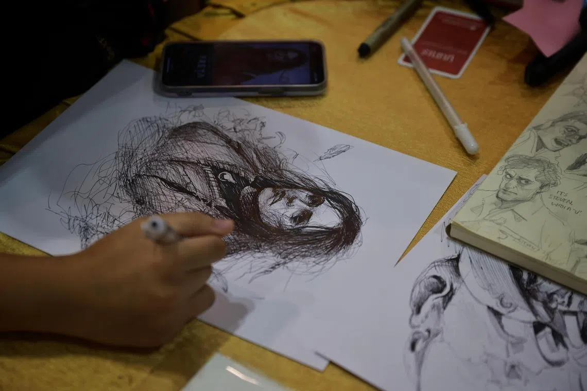 An artist sketching a portrait while manning a booth in Artist Alley during Singapore Comic Con at the Sands Expo & Convention Centre on Sunday (Dec 11, 2022). 