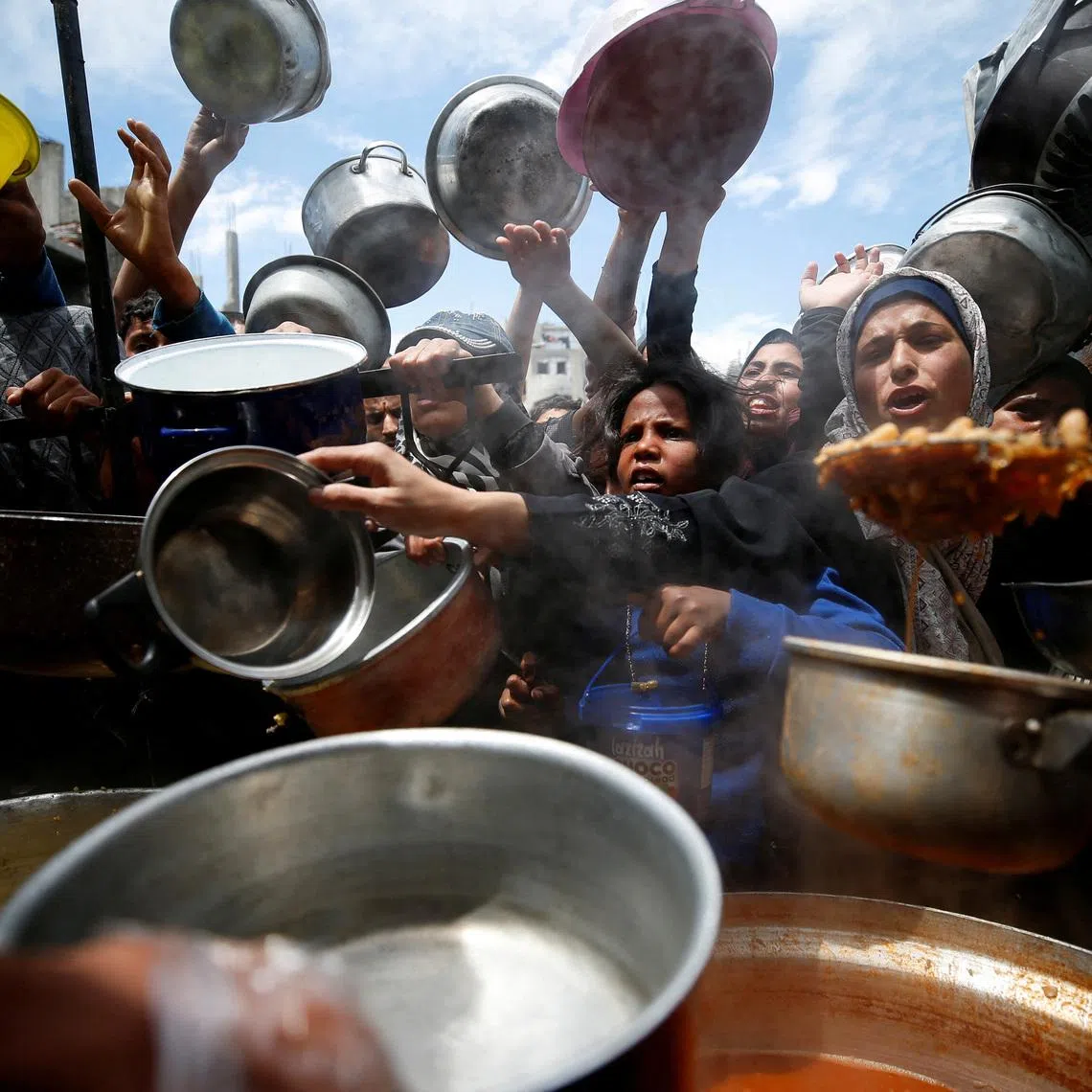 FILE PHOTO: Palestinians wait to receive food cooked by a charity kitchen, in Beit Lahiya, northern Gaza Strip, April 28, 2025. REUTERS/Mahmoud Issa/File Photo