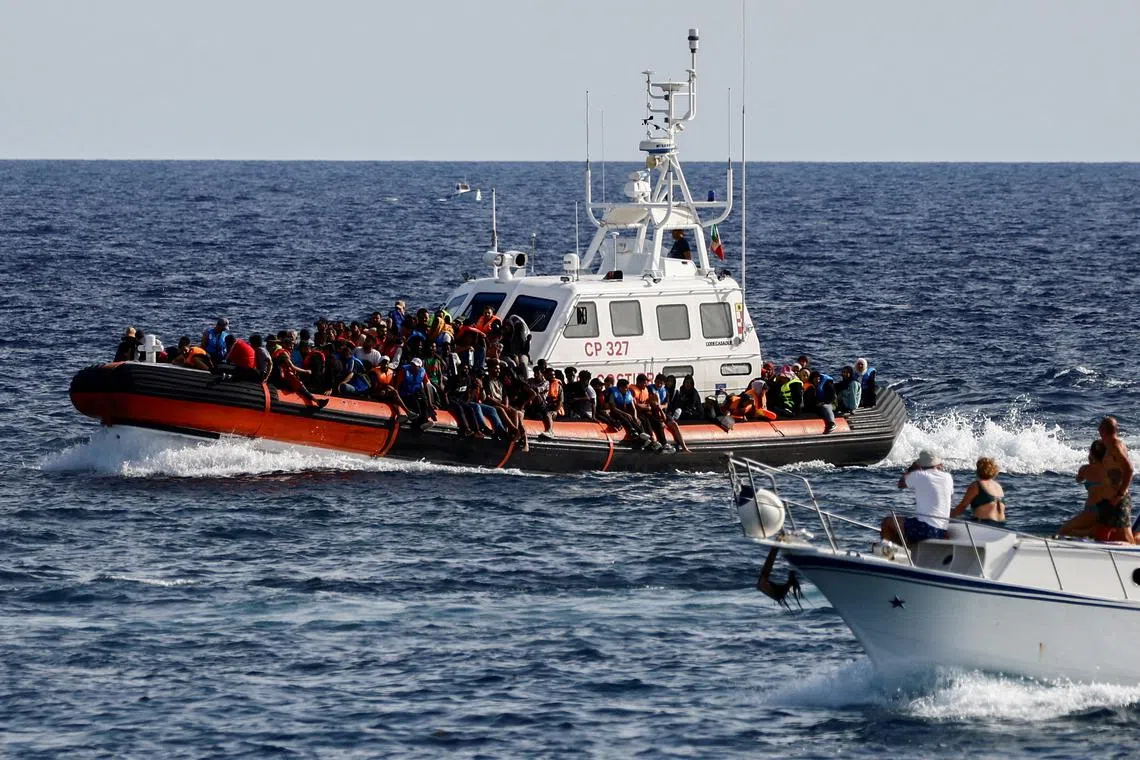 FILE PHOTO: An Italian Coast Guard vessel carrying migrants rescued at sea passes near a tourist boat, on the Sicilian island of Lampedusa, Italy, September 18, 2023. REUTERS/Yara Nardi//File Photo