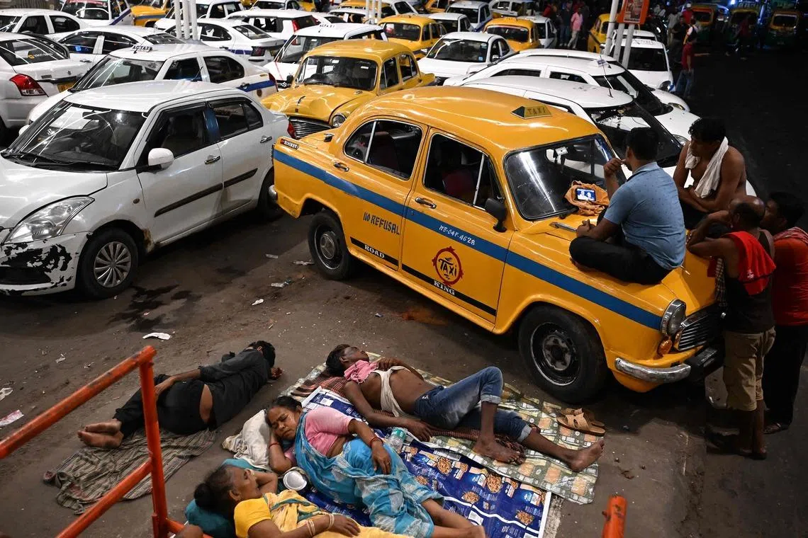 TOPSHOT - Drivers of Kolkata's iconic Hindustan Ambassador yellow taxi watch the 2026 World Cup football tournament semi-final match between England and Argentina on a mobile phone, at a taxi-stand in Kolkata on July 16, 2026. (Photo by Dibyangshu SARKAR / AFP)