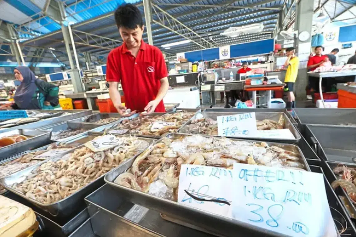Mr Teo sorting through sea prawns at his stall at the Taman Perling wet market in Johor Baru. The oversupply of wild prawns have caused a price reduction since June.