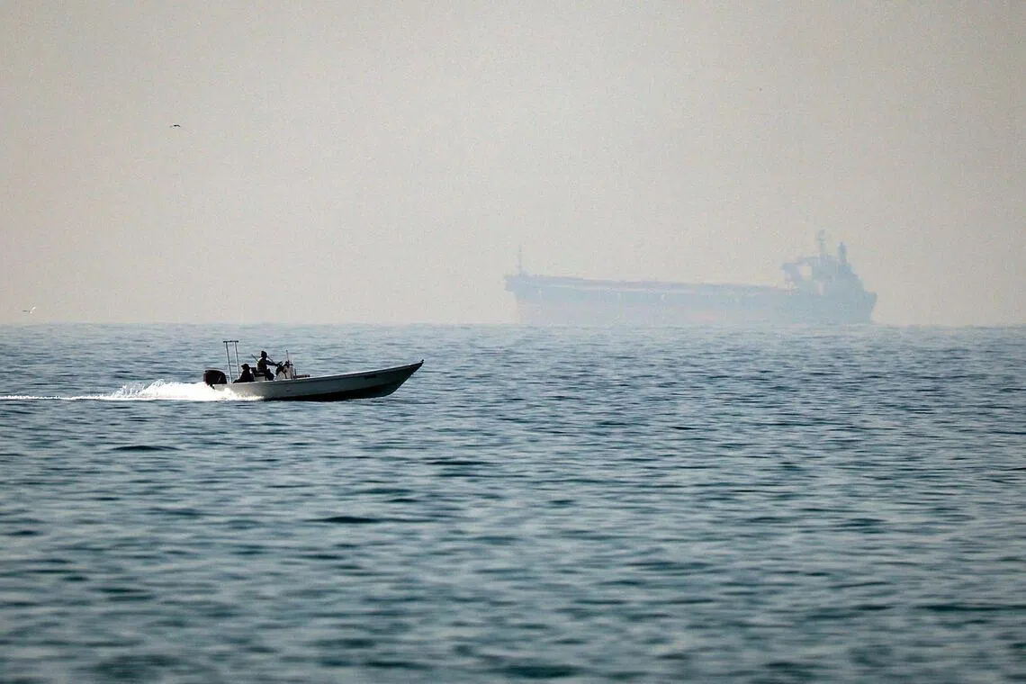 A motorboat cruises along off the town of Al Jeer on the Strait of Hormuz, with a tanker in the background, on Feb 25.