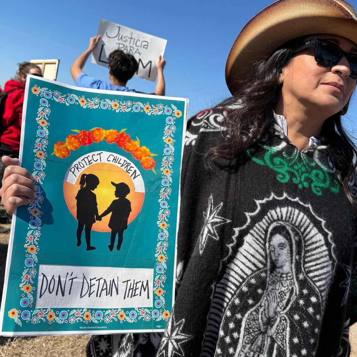 A person holds a sign calling to protect, not detain, children as people gather during a demonstration and vigil outside the South Texas Family Residential Center in Dilley, Texas, on Jan 28, 2026. 
