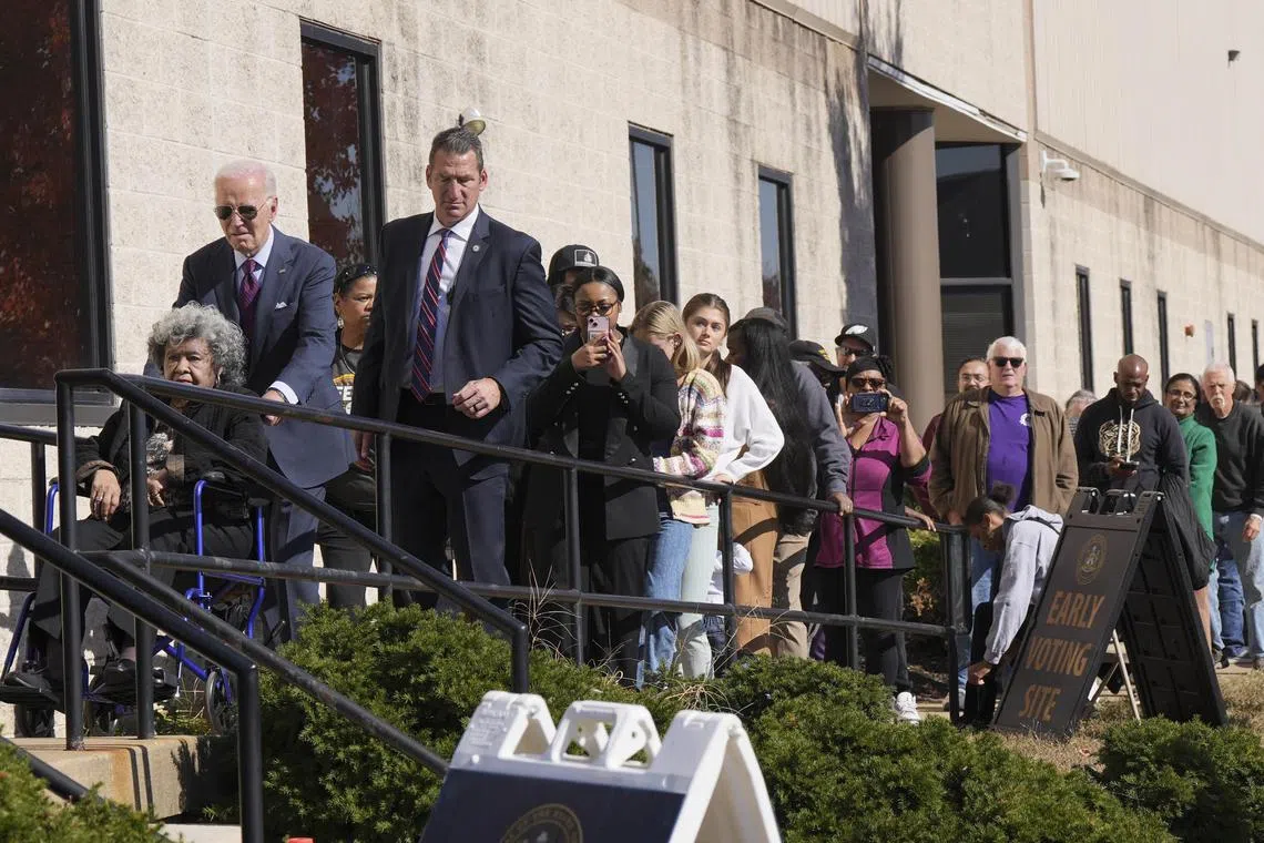 Mr Biden pushes a woman in a wheelchair as he waits in line in to cast his ballot at an early-voting centre in Delaware. 