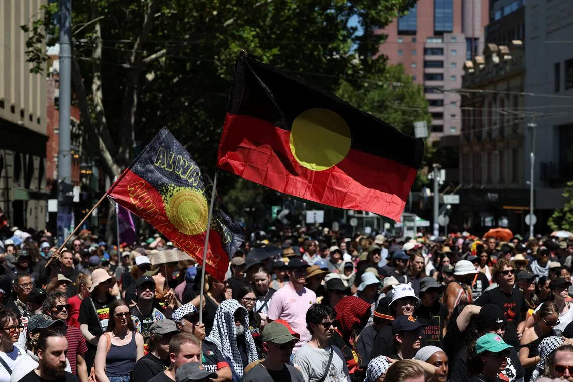 A man holds an Australian Aboriginal flag as protestors gather for an "Invasion Day" rally on Australia's national day in Melbourne, Australia.