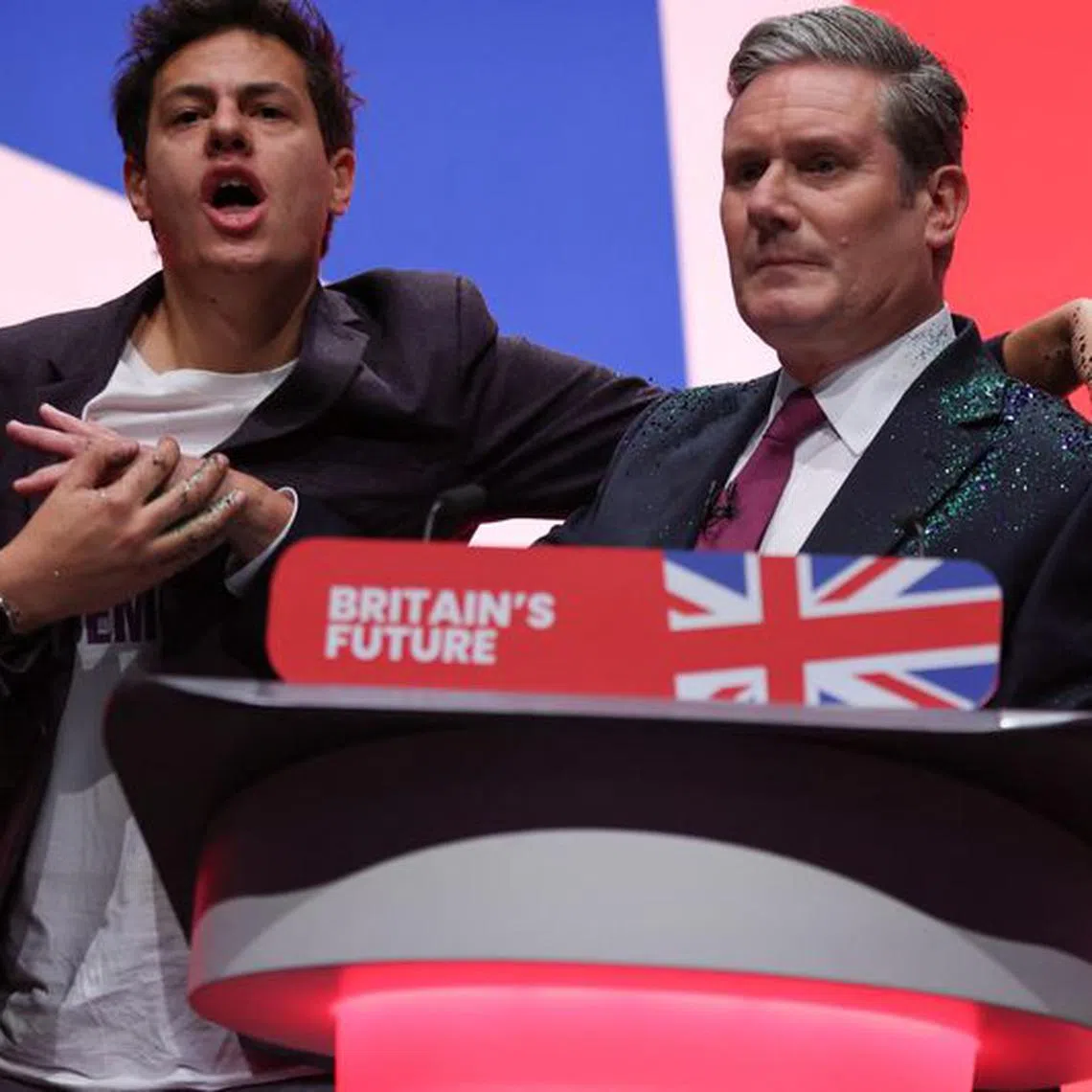A protester stands next to Britain's Labour Party Leader Keir Starmer at Britain's Labour Party annual conference in Liverpool, Britain, October 10, 2023. REUTERS/Phil Noble
