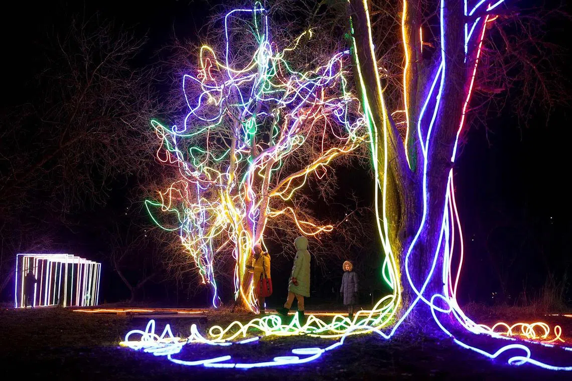 People walking through a park decorated with light installations in Kyiv, Ukraine, on Dec 28, 2023, amid the Russian invasion of Ukraine. 