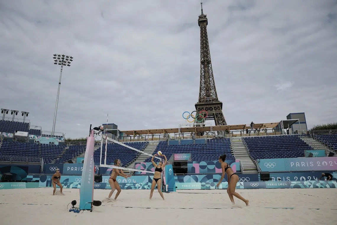 A beach volleyball training session takes place against the backdrop of the grandeur of the Eiffel Tower, as Paris prepares to host a transformative Games.