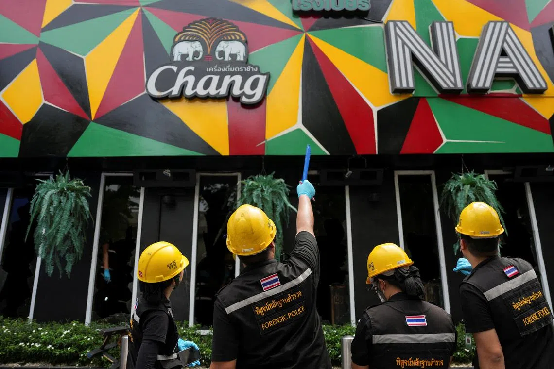 Forensic police officials inspect the site of a deadly fire at a pub in Bangkok, Thailand, July 13.