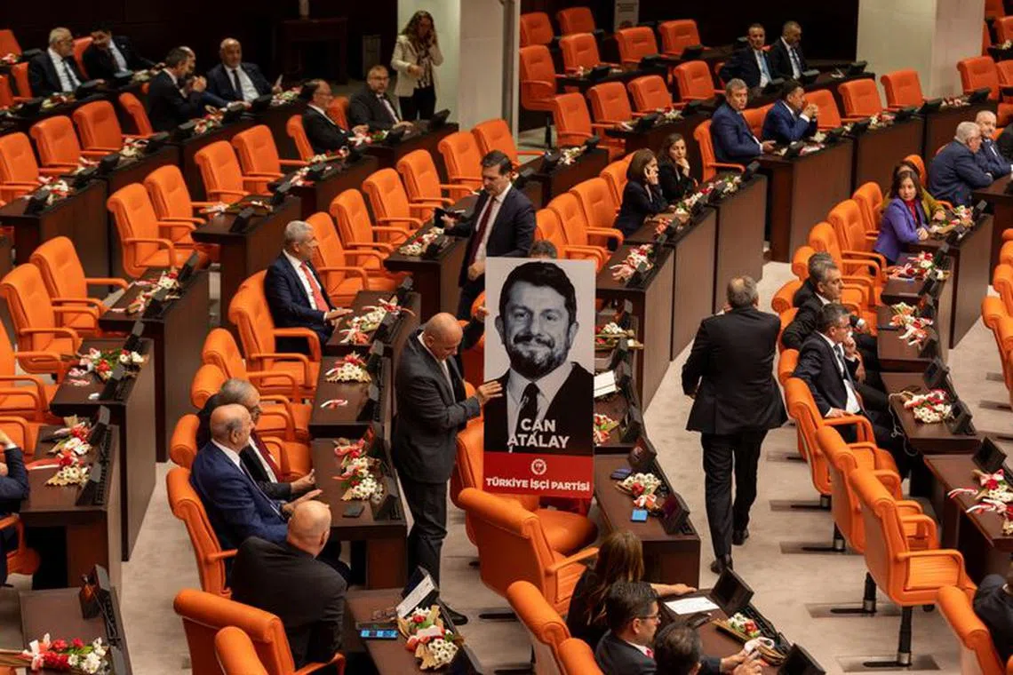 FILE PHOTO: Erkan Bas, the leader of Workers' Party of Turkey (TIP) and his party MPs Sera Kadigil and Ahmet Sik display a portrait of Can Atalay, a jailed MP of TIP, during a swearing-in ceremony at the Turkish parliament in Ankara, Turkey, June 2, 2023. REUTERS/Umit Bektas/File photo