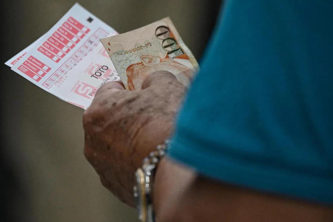 A man holds his tickets while queueing on the last day to place bets for the TOTO Hong Bao Draw 2023, at the Singapore Pool Outlet at the Toa Payoh HDB Centre on Feb 3, 2023.