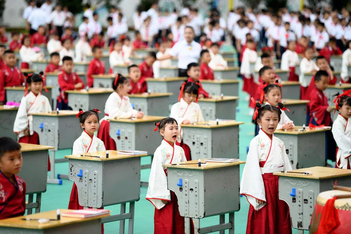 First-grade students wearing Hanfu clothing take part in an initiation ceremony to learn about traditional culture at a primary school in Anlong County, in China’s southwest Guizhou Province.