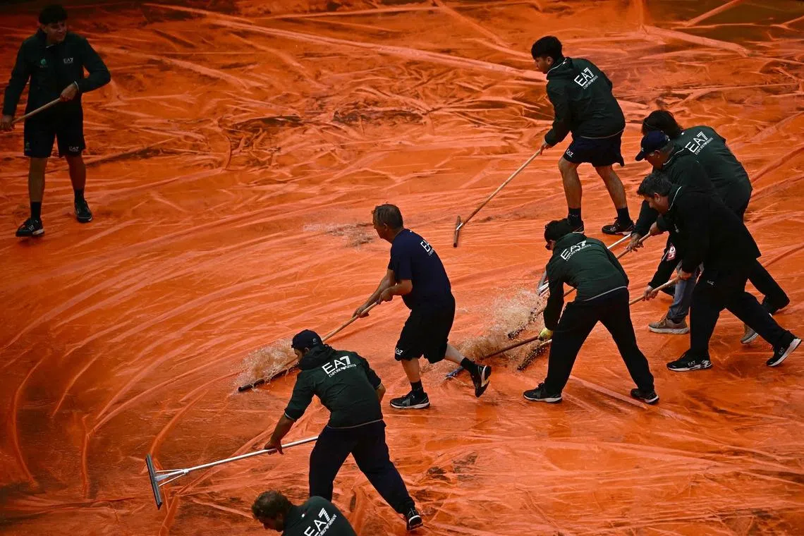 Staff removing water from the tarp covering the clay court after the semi-final match between Italy's Luciano Darderi and Norway's Casper Ruud was interrupted due to a storm during the ATP Rome Open tennis tournament at Foro Italico in Rome, Italy on May 15, 2026. 