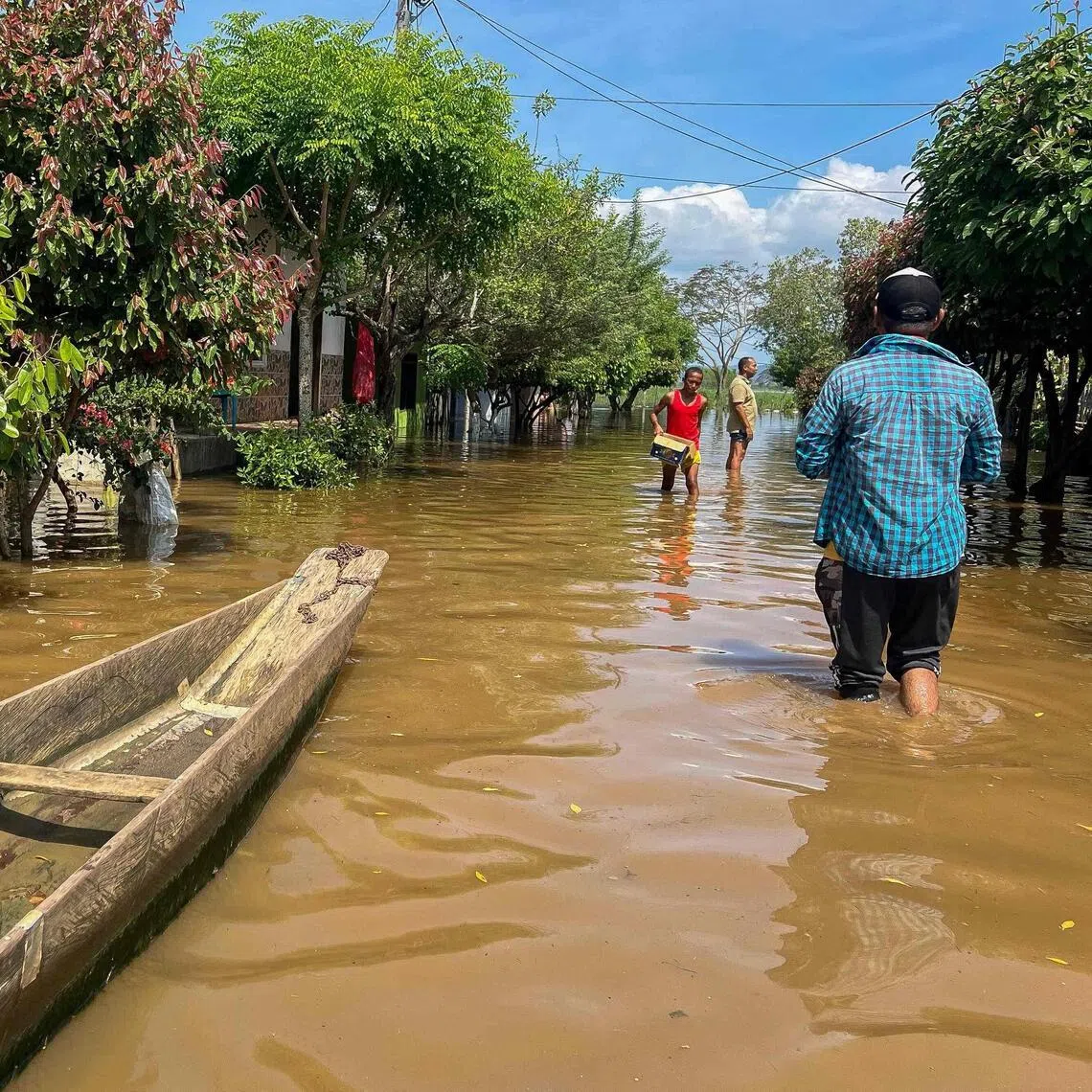 People walking on a flooded street in Lorica, in Colombia's Cordoba department, on Feb 9.