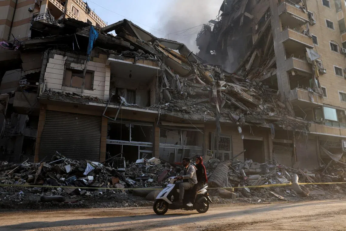 People ride a scooter past damaged buildings, in the aftermath of Israeli strikes on Beirut's southern suburbs, during a Hezbollah media tour, amid the ongoing hostilities between Hezbollah and Israeli forces, Lebanon, November 9, 2024. REUTERS/Mohamed Azakir/File Photo