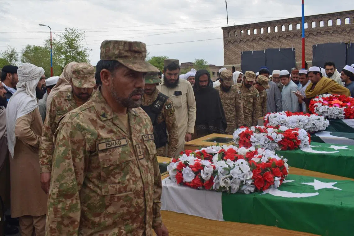 Relatives and security gather around coffins of policemen who were killed by a roadside bomb in Lakki Marwat, Khyber Pakhtunkhwa, on March 30.