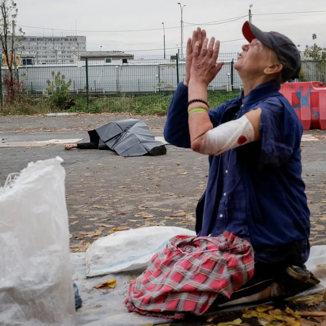 SENSITIVE MATERIAL. THIS IMAGE MAY OFFEND OR DISTURB A wounded street vendor reacts as the body of another street vendor lies on the ground next to goods at the site of a flea market hit during a Russian military strike, amid Russia's attack on Ukraine, in Kharkiv, Ukraine October 16, 2026. REUTERS/Sofiia Gatilova