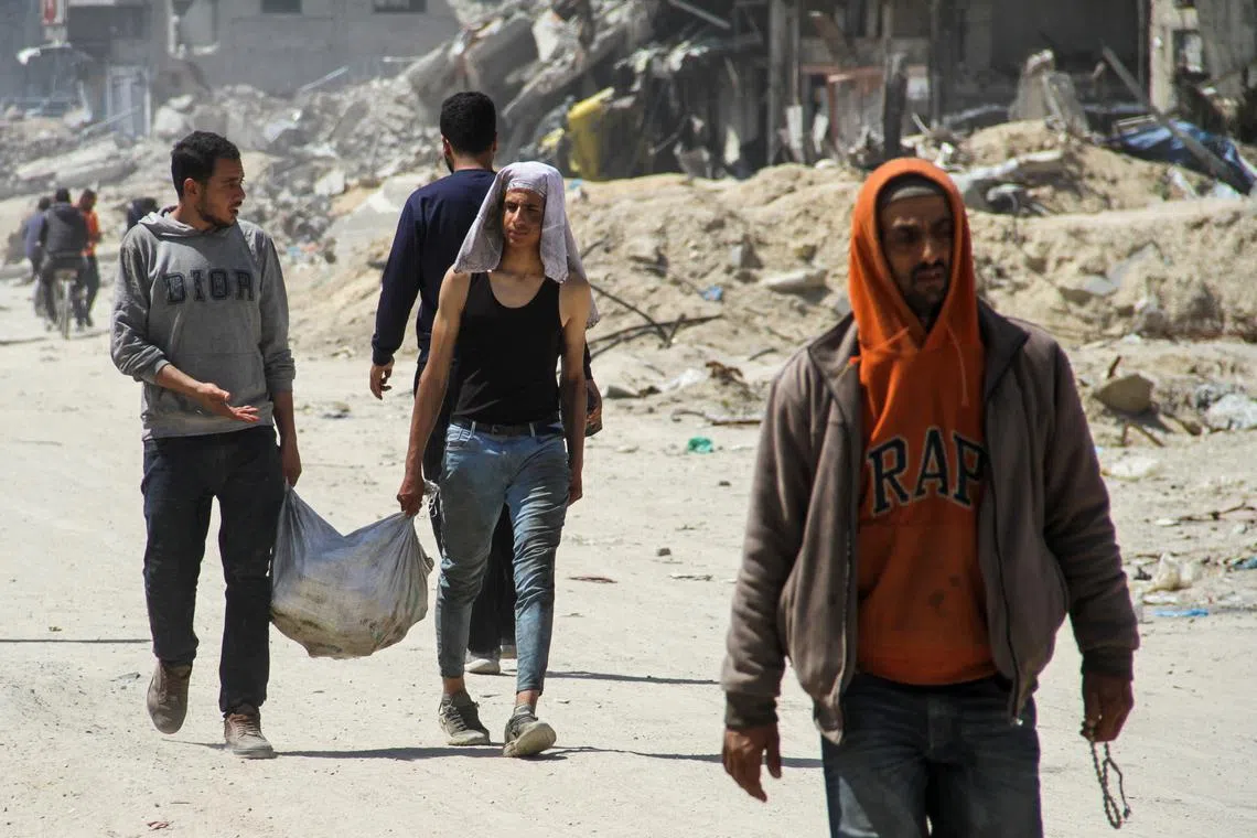 Palestinians carry a bag of aid as others struggle to receive their portion amid a widespread hunger, as the conflict between Israel and the Palestinian Islamist group Hamas continues, in Gaza City April 3, 2024. REUTERS/Mahmoud Issa/File Photo