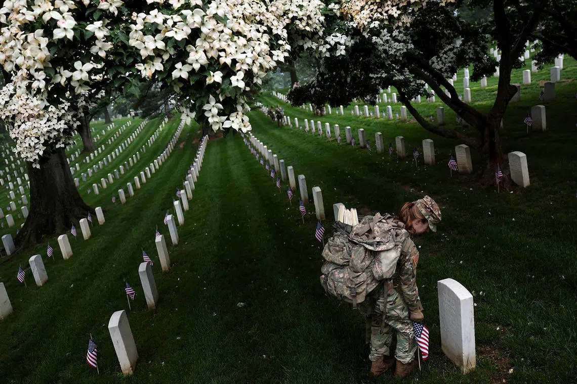 A soldier from the US Army 3d Infantry Regiment, known as The Old Guard, participating in the annual Flags-In event where US flags are placed at service members' gravesites, ahead of Memorial Day at Arlington National Cemetery in Arlington, Virginia, US, May 22, 2025. 