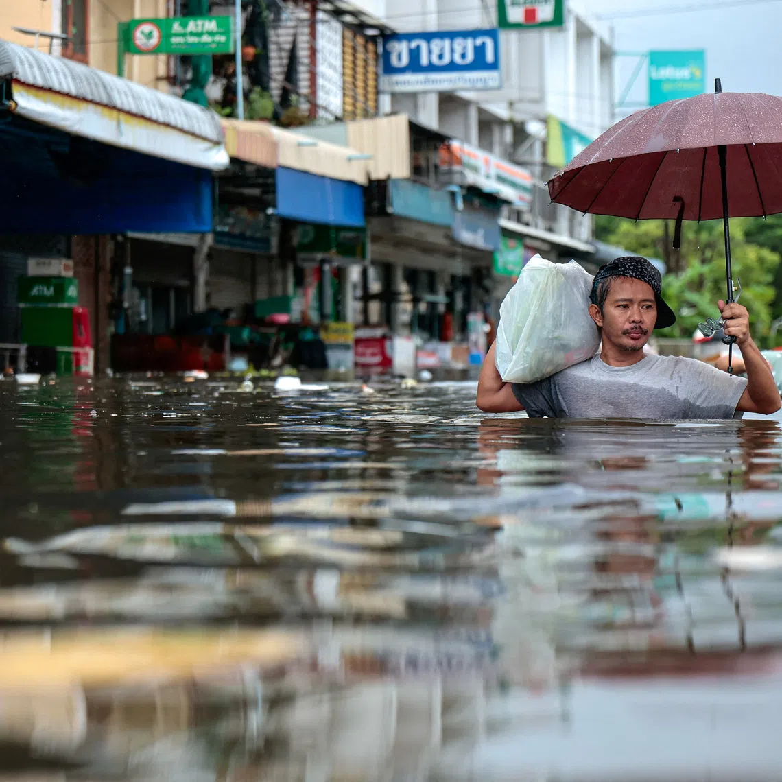 People wade through a flooded area during heavy rain in Bangkok, Thailand, September 27, 2026. REUTERS/Patipat Janthong