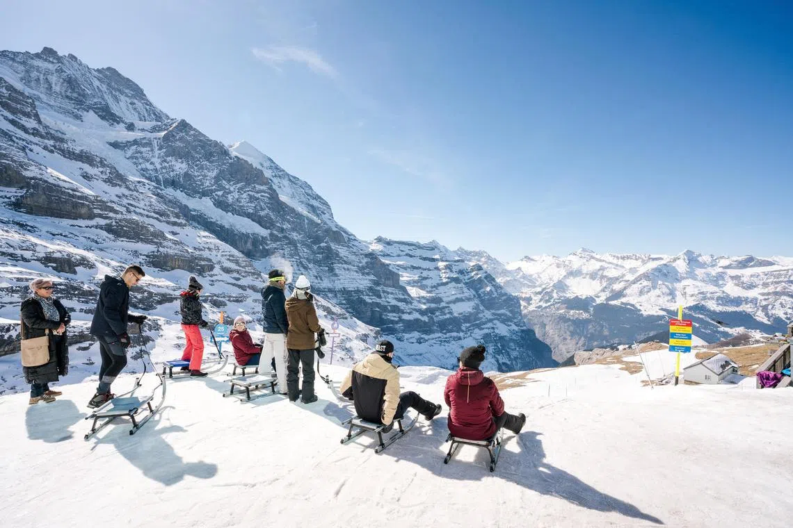 Sledders prepare to descend run No. 68 at the Eiger mountain glacier, near Grindelwald, Switzerland, March 4, 2023. There is nothing tame about sledding in Switzerland, where participants rocket down steep, miles-long slopes, sometimes at night. (Clara Tuma/The New York Times)