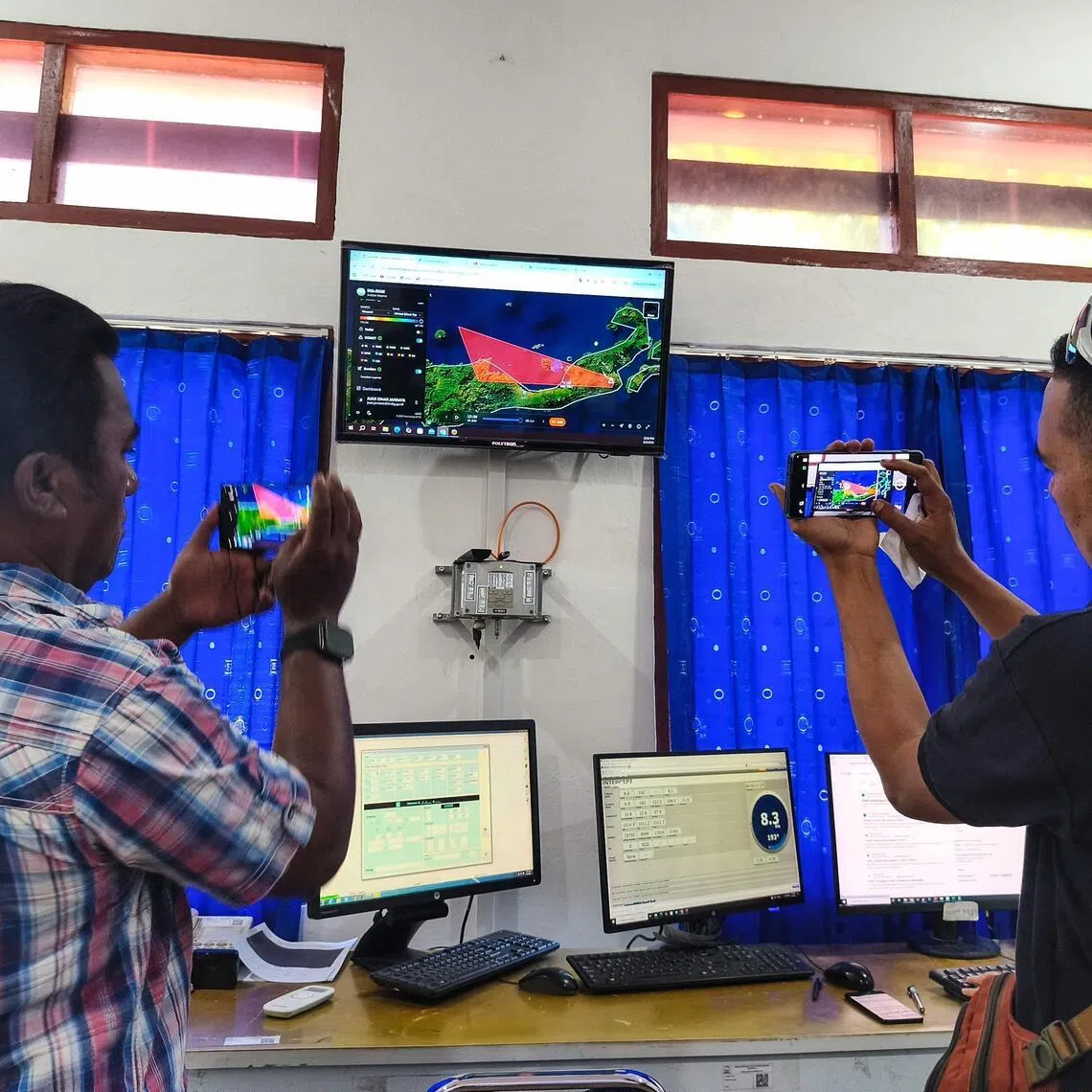 Journalists photograph a screen showing the movement of volcanic ash from Mount Lewotobi Laki-laki at the Meteorology, Climatology and Geophysics Agency (BMKG) office in East Nusa Tenggara.