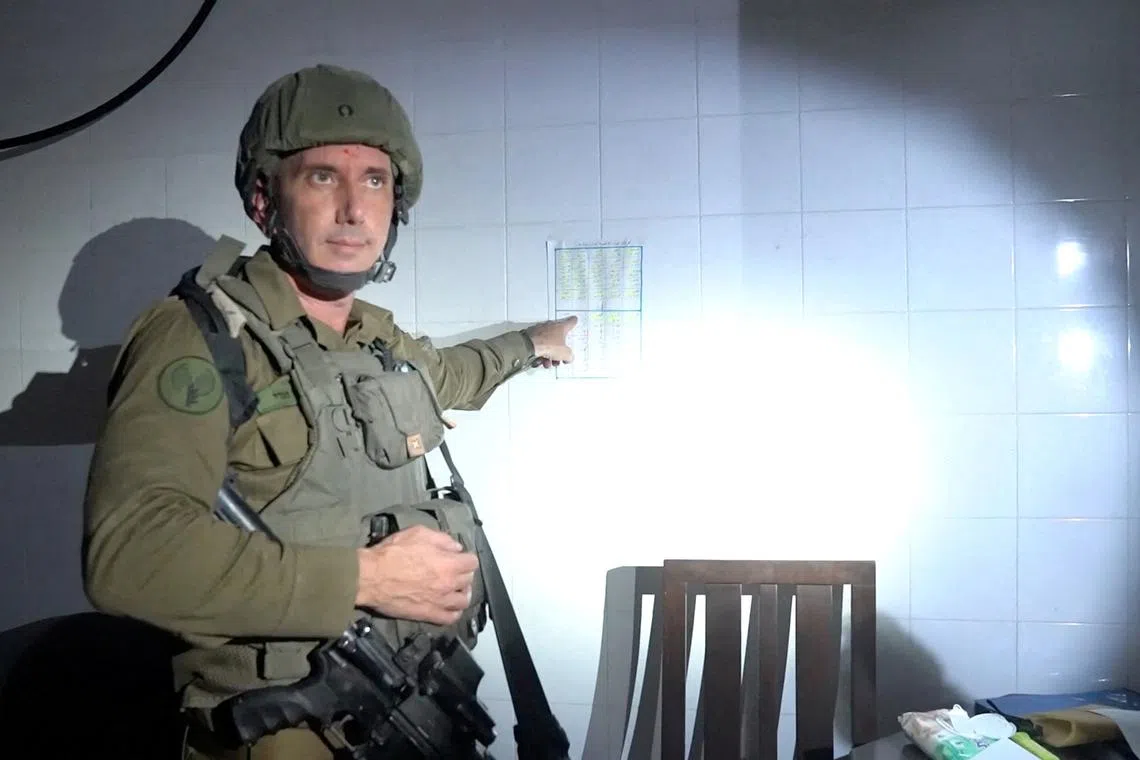 Israeli military spokesperson Rear Admiral Daniel Hagari points at what he says is a guard roster in a room the military suspects was used by Hamas to hold hostages in the basement of Rantissi Hospital, a paediatric hospital with a specialty in treating cancer patients, at a location given as Gaza, in this still image taken from video released November 13, 2023.   Israel Defense Forces/Handout via REUTERS/File Photo