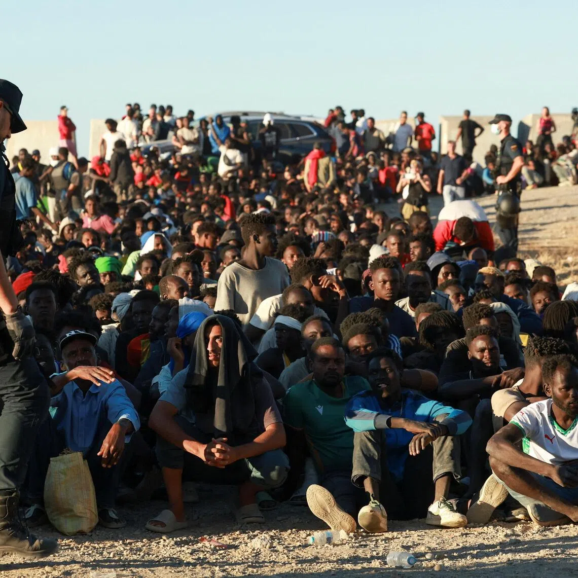 Migrants wait to receive food and beverage from the Red Cross, following mass crossings from Morocco into Spanish territory, in Ceuta, Spain, on Aug 3.