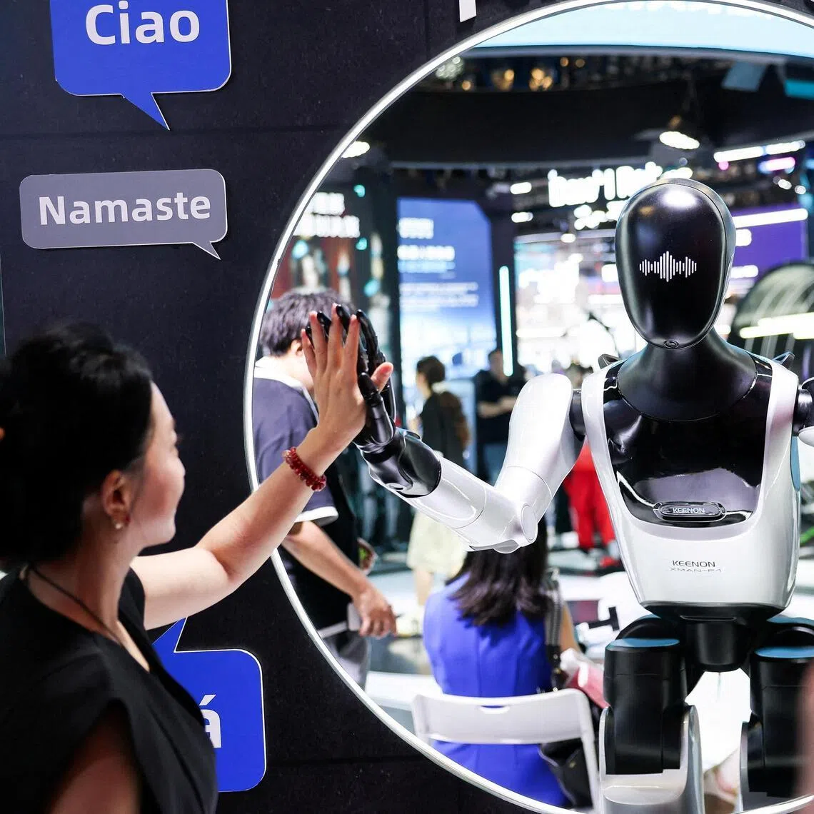 A visitor high-fives a humanoid robot at the Keenon Robotics booth during the World Artificial Intelligence Conference (WAIC) in Shanghai, China, July 18.