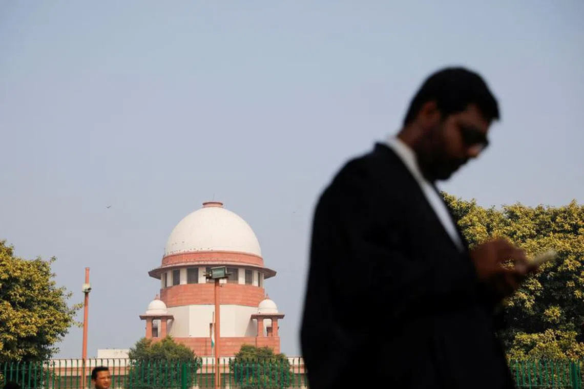 A lawyer looks into his mobile phone in front India's Supreme Court in New Delhi, December 11, 2023. REUTERS/Adnan Abidi