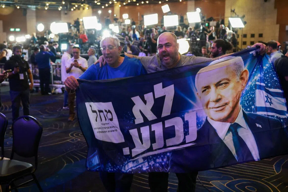 Supporters holding a banner featuring Israeli Prime Minister Benjamin Netanyahu react to exit poll results at Netanyahu’s Likud party headquarters in Jerusalem on Oct 27.