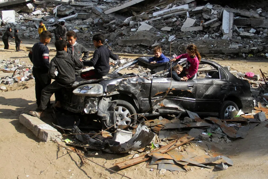 Palestinian children play in a destroyed car near the rubble of houses destroyed in previous Israeli strikes, amid ceasefire negotiations with Israel, in Gaza City, January 15, 2025. REUTERS/Mahmoud Issa