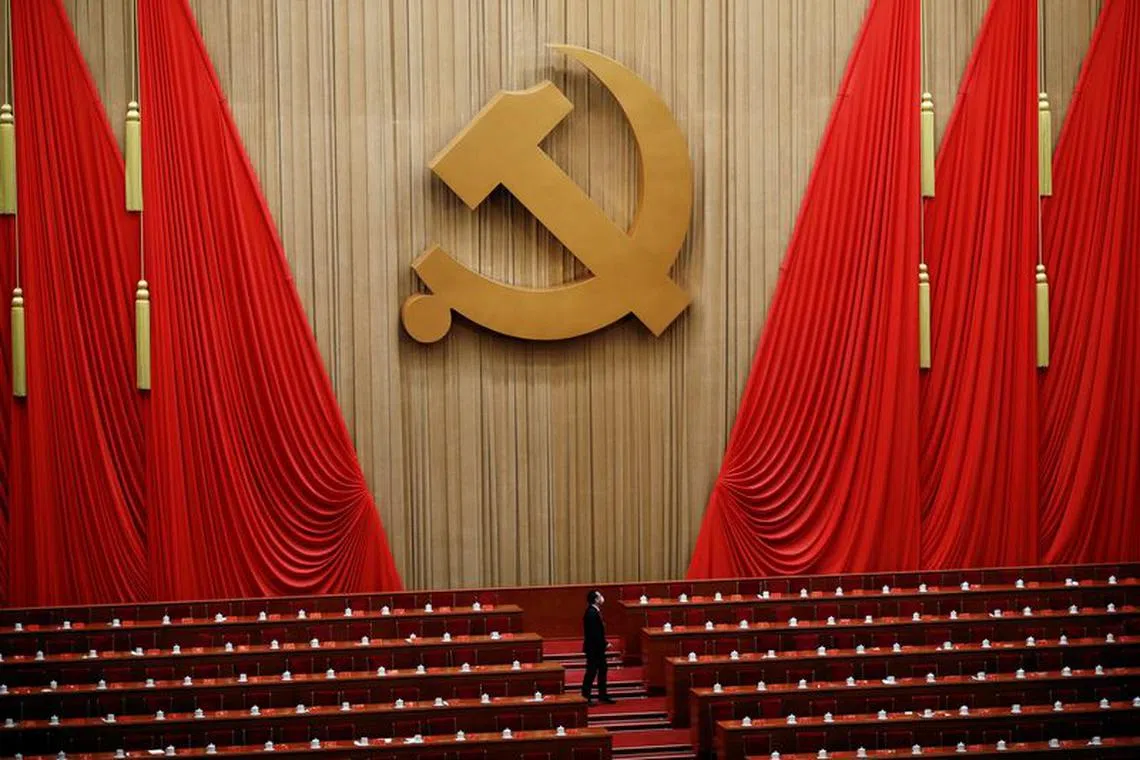 A man stands under the Chinese Communist Party emblem at the end of the closing ceremony of the 20th National Congress of the Communist Party of China, at the Great Hall of the People in Beijing, China October 22, 2022. REUTERS/Tingshu Wang
