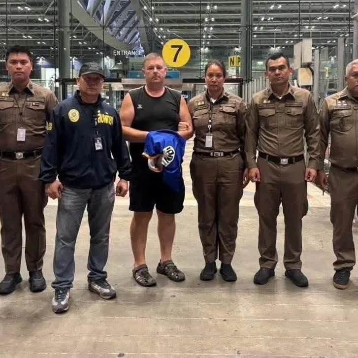 Police officers pose with Carman Simon Peter, an Australian man arrested in the suspected murder of a 17-year-old Thai girl in Pattaya, at Suvarnabhumi International Airport, in Samut Prakan, Thailand June 27, 2026.   Pattaya Provincial Police/Handout via REUTERS