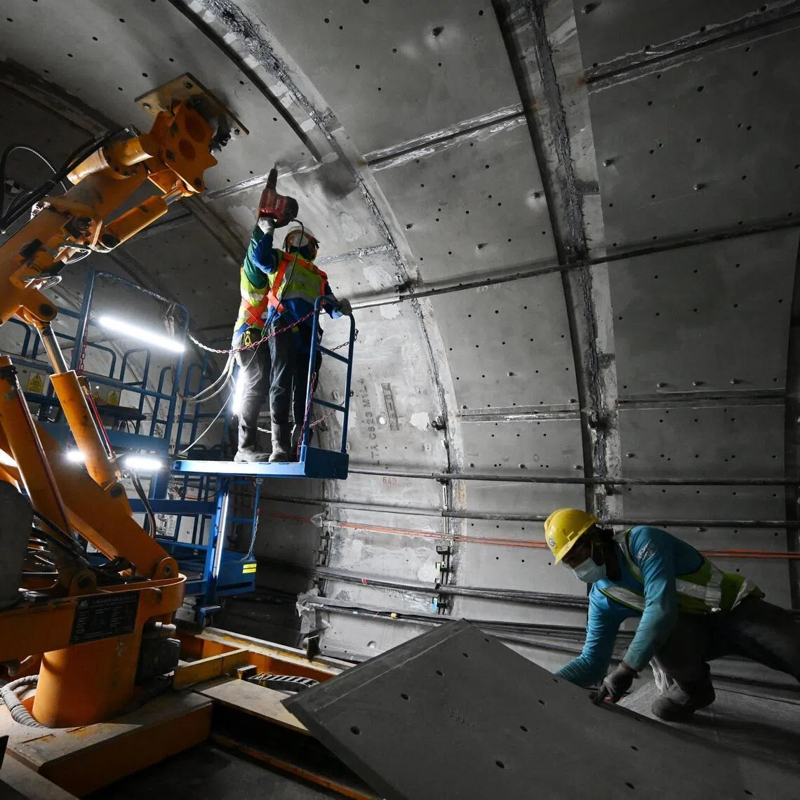 Workers installing one of the final steel plates, with the help of a robotic arm, in a tunnel at the Dakota MRT station on Feb 9, 2026.