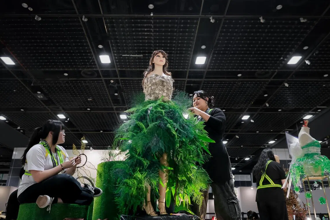 ITE College Central Year 2 Nitec in Floristry student Chua Zhi En Sera (right) with her team's Bark Forest Fairy dress on a mannequin on Aug 1, 2024, for the Wearable Floral Art Showcase by the Singapore Garden Festival held at Suntec Singapore Convention & Exhibition Centre.