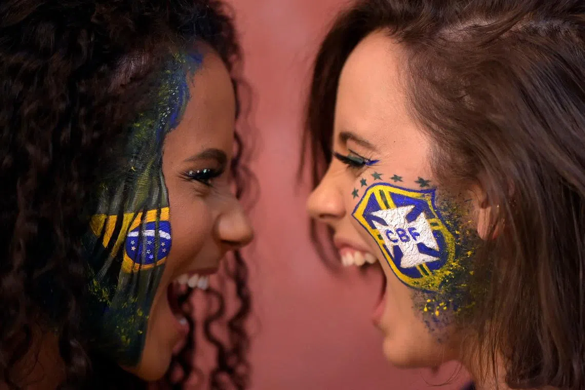 Makeup artist Natalia Bastos (right), who creates themed make-up for the 2022 World Cup in Qatar, poses in her studio with client Milene Cristina in Belo Horizonte, Brazil.