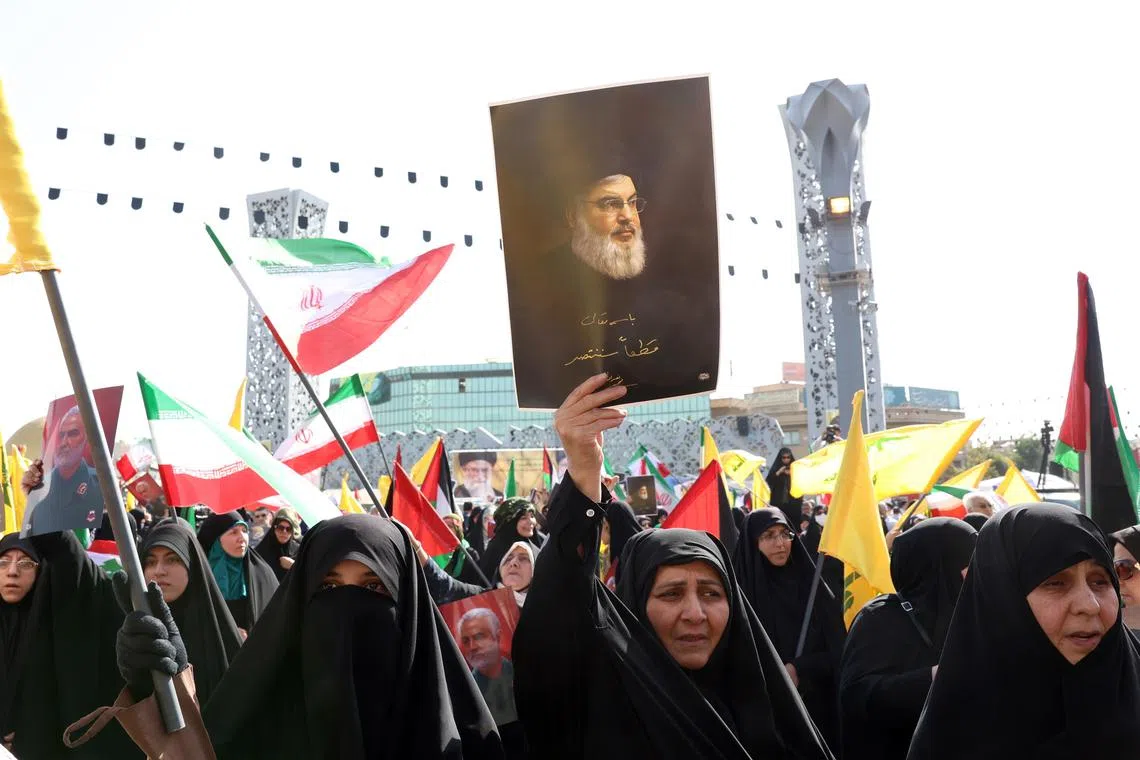 An Iranian woman holding up a picture of late Hezbollah leader Hassan Nasrallah, during an anti-Israeli rally in Tehran after Iran's Oct 1 missile attack on Israel.