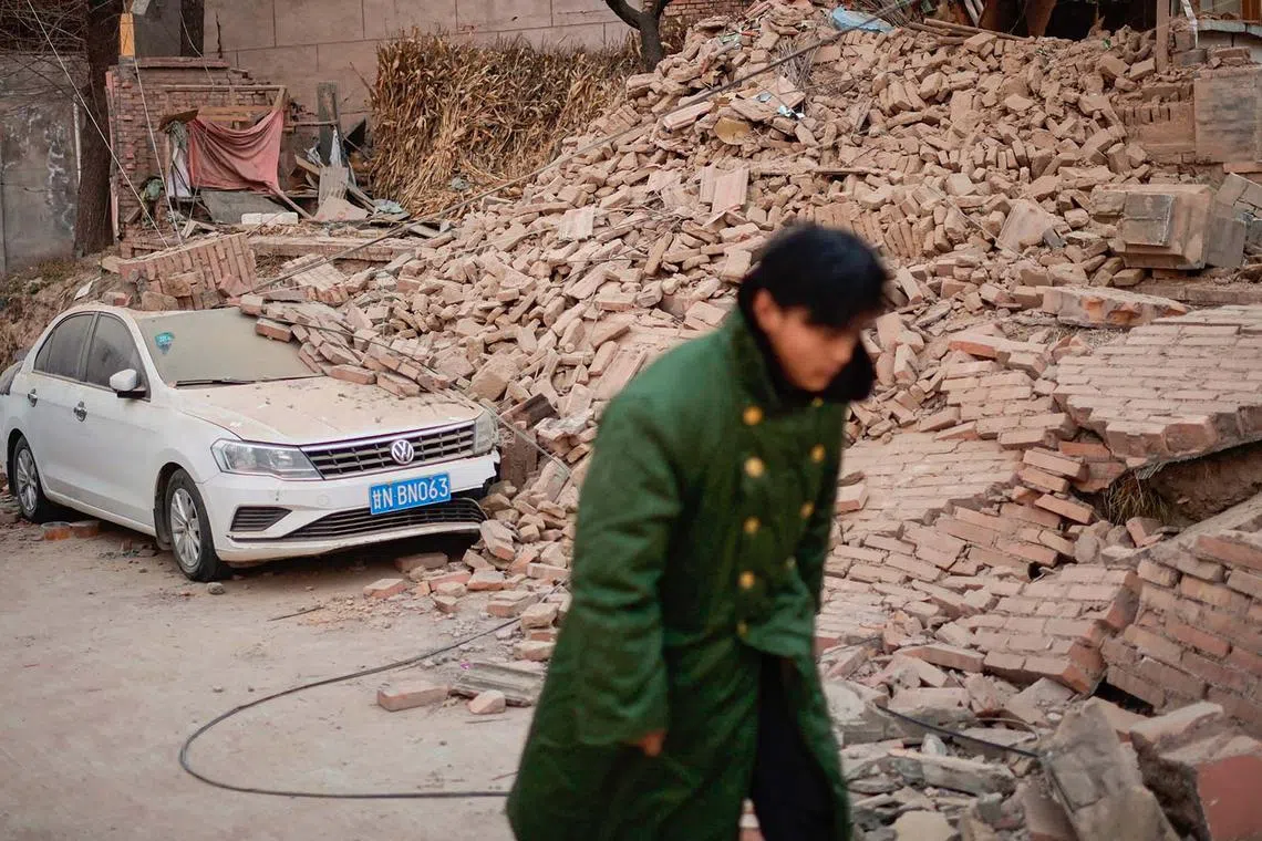 TOPSHOT - A man walks past a collapsed house in Dahejia in Jishishan County in northwest China's Gansu province on December 20, 2023. Survivors of China's deadliest earthquake in years huddled in aid tents on December 20 after overnight temperatures plunged well below zero, with the death toll rising to 131. (Photo by Pedro Pardo / AFP)