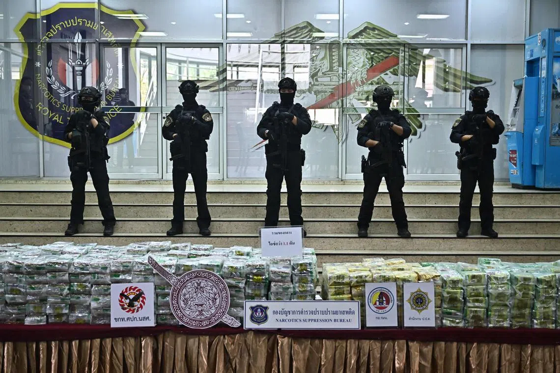 Anti-illegal drugs agents stand guard as packages of crystal methamphetamine are presented during a news conference in Bangkok.