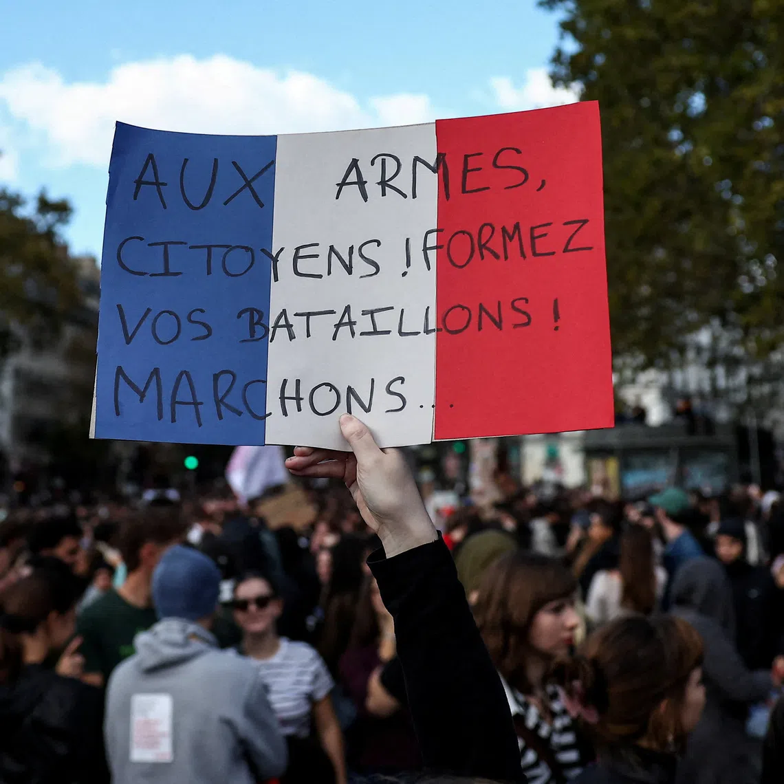 A protester holds a placard in the colours of the French flag reading \"To arms, citizens! Form your battalions! Let's march\", during a demonstration by French high school and university students in Paris as part of a nationwide day of protests and blockades supported by teachers and school parents to demand better school conditions in France, October 8, 2026. REUTERS/Abdul Saboor